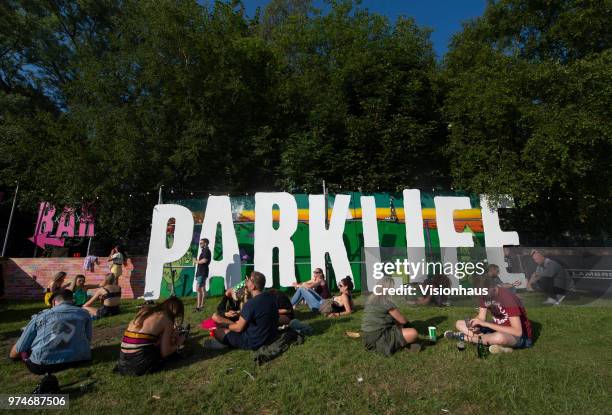 Festival goers soak up the sun in front of a Parklife sign in the VIP area on day one of the Parklife Festival at Heaton Park on June 9, 2018 in...