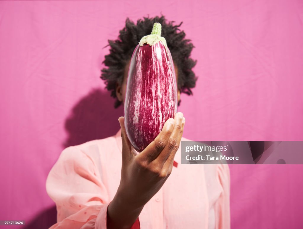 Woman holding aubergine in front of face