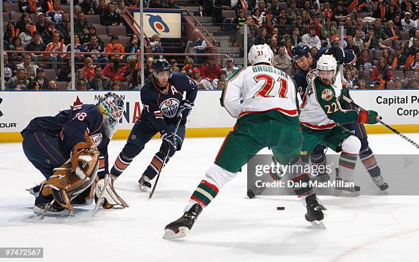 Jeff Deslauriers of the Edmonton Oilers keeps an eye on the puck along with teammates Tom Gilbert and Aaron Johnson as Cal Clutterbuck and Kyle...