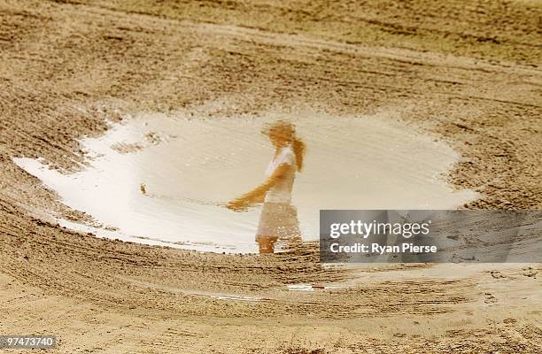 Florentyna Parker of England is seen reflected in a flooded bunker as she chips onto the 2nd green during round three of the 2010 ANZ Ladies Masters...