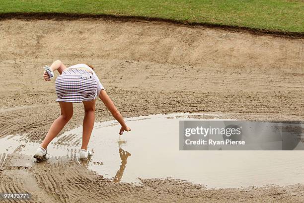 Florentyna Parker of England picks her ball out of a flooded bunker on the 2nd hole during round three of the 2010 ANZ Ladies Masters at Royal Pines...