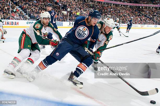 Brent Burns of the Minnesota Wild fight for the puck with Marc Pouliot of the Edmonton Oilers at Rexall Place on March 5, 2010 in Edmonton, Alberta,...