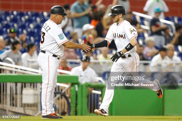 Riddle of the Miami Marlins high fives third base coach Fredi Gonzalez after hitting a solo home run in the fifth inning against the San Francisco...