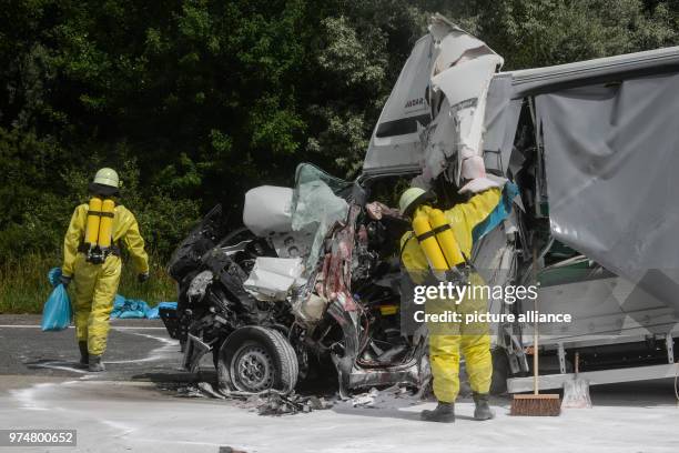 June 2018, Germany, Werder : Emergency personnel of the fire brigade in special suits work on an accident involving a van and a transport of...