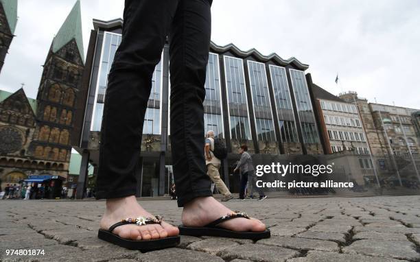 June 2018, Germany, Bremen: A woman wearing flip-flops standing at the Marktplatz outside the Bremen Buergerschaft legislative assembly. Shorts,...