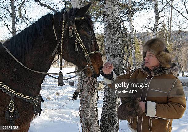 Picture released on March 6, 2010 shows Russian Prime Minister Vladimir Putin stroking a horse in the Karatash area, near the town of Abakan, during...