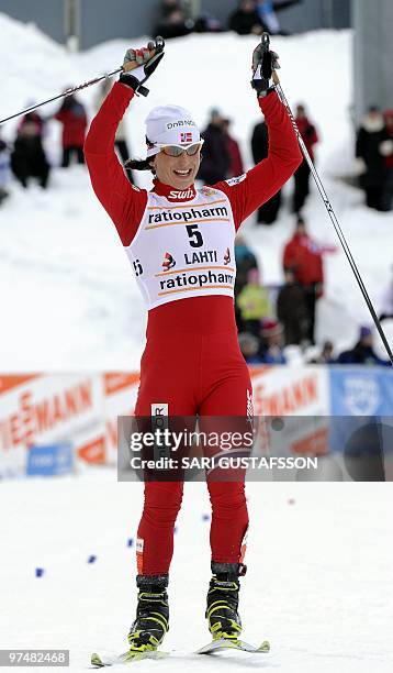 Marit Björgen of Norway celebrates as she crosses the finish line to win the ladies' cross country pursuit at the FIS World Cup Lahti Ski Games, in...