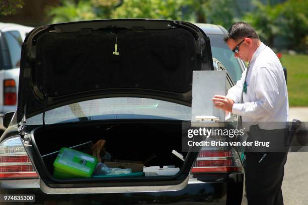 Los Angeles Sheriff's homicide detective flips through papers on the trunk of his car outside a home at 8620 Santa Susana Place June 8 2012 in Canoga...