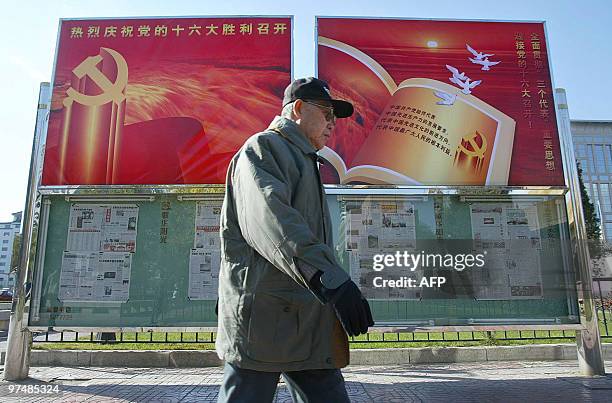 Man walks past billboards announcing the start of the Communist Party's 16th National Congress and Chinese President Jiang Zemin's theory of "Three...