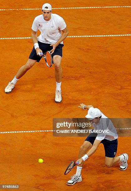 Player John Isner watches as his partner Bob Bryan returns the ball to Serbia's double Nenad Zimonjic and Janko Tipsarevic during their Davis Cup...