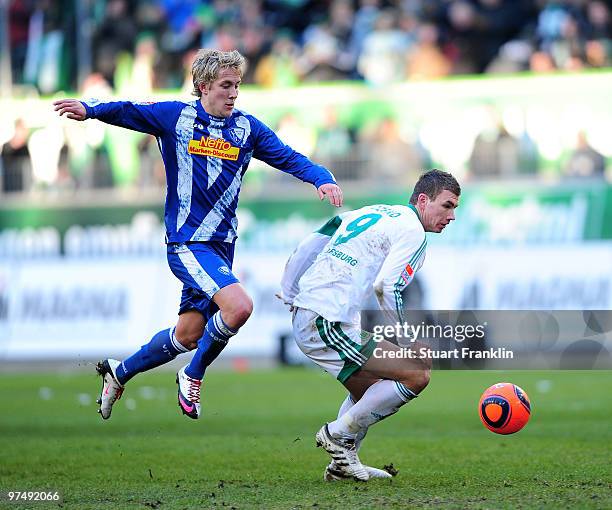 Edin Dzeko of Wolfsburg is challenged by Lewis Holtby of Bochum during the Bundesliga match between VfL Wolfsburg and VfL Bochum at Volkswagen Arena...