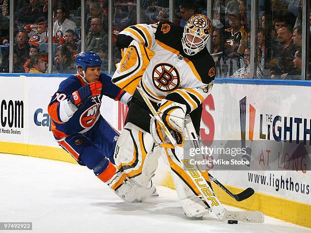 Goaltender Tim Thomas of the Boston Bruins plays the puck behind the net as he's being pursued by Richard Park of the New York Islanders on February...