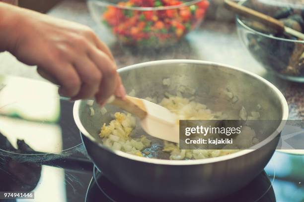 jonge vrouw voorbereiding paella - garlic stockfoto's en -beelden