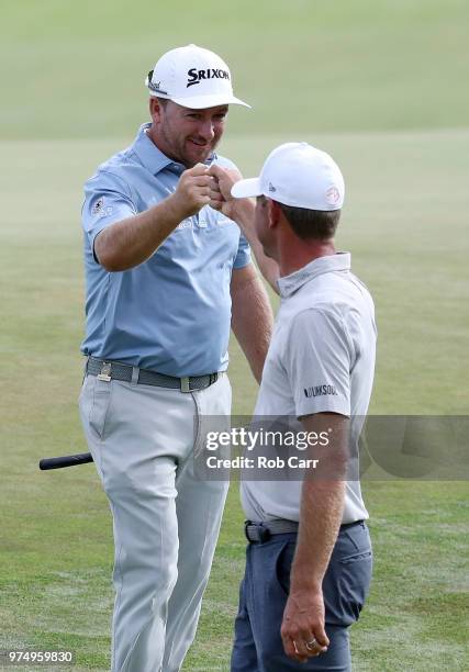 Graeme McDowell of Northern Ireland high-fives Lucas Glover of the United States after putting out on the fifth hole during the first round of the...