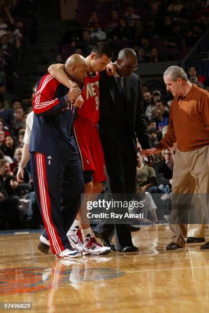 Jarvis Hayes and Assistant Coach Roy Rogers, and Head Athletic Trainer Tim Walsh helps Yi Jianlian of the New Jersey Nets off the court as he is...