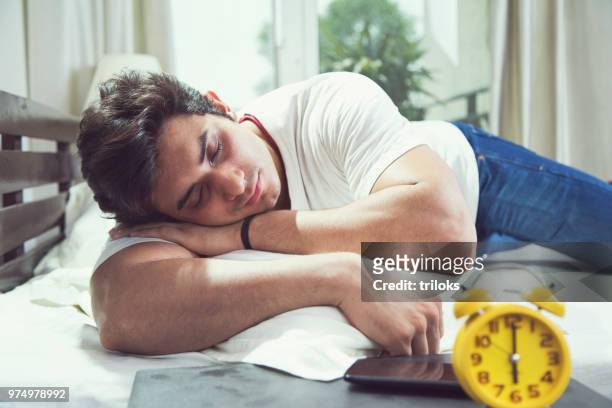 alarm clock with man sleeping on bed - sleeping man stock pictures, royalty-free photos & images