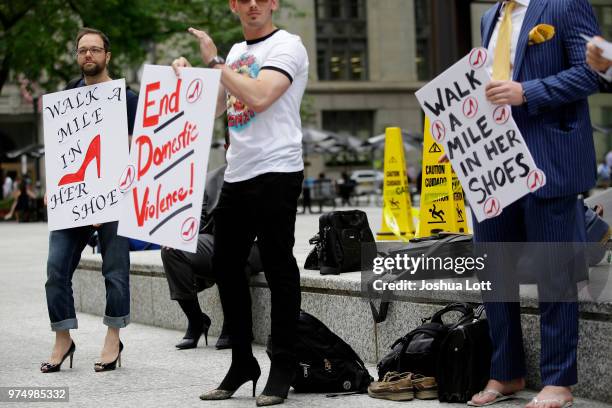 Male attorneys stand in women's high heel shoes as they hold signs to raise awareness of sexual assault against women on June 14, 2018 in Chicago,...