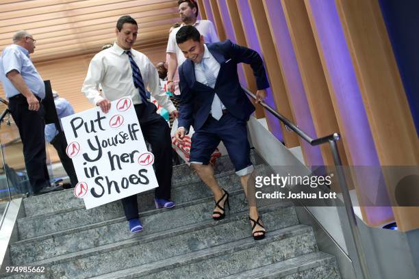 Male attorneys walk down stairs in women's high heel shoes to raise awareness of sexual assault against women on June 14, 2018 in Chicago, Illinois....