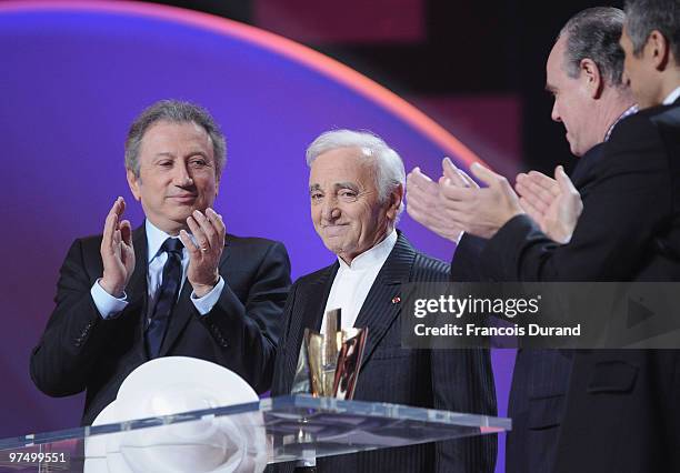 French TV hosts Nagui and Michel Drucker listen to French culture minister Frederic Mitterrand annoucing an award of honor for French singer Charles...