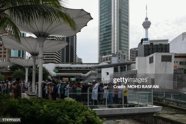 Muslims offer Eid al-Fitr prayers as Kuala Lumpur Tower looming on the background at the Jamek Mosque in Kuala Lumpur on June 15, 2018. - Eid al-Fitr...