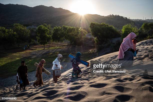 Muslims walk on 'sea of sands' as they prepare for Eid Al-Fitr prayer at Parangkusumo beach on June 15, 2018 in Yogyakarta, Indonesia. Muslims around...