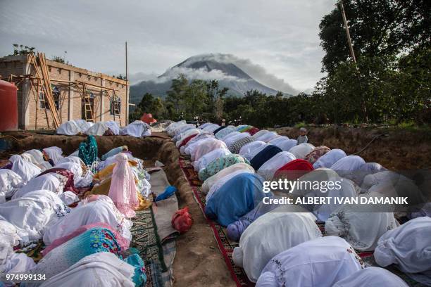 Indonesian Muslims take part in a prayer celebrating the Eid al-Fitr festival near Mount Sinabung in Karo, North Sumatra, on June 15, 2018. -...