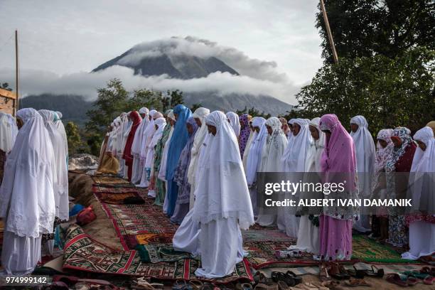 Indonesian Muslims take part in a prayer celebrating the Eid al-Fitr festival near Mount Sinabung in Karo, North Sumatra, on June 15, 2018. -...