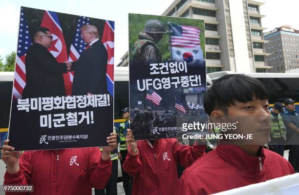South Korean activists hold placards showing images of the Trump-Kim summit and a South Korea-US joint military drill during a rally to demand a halt...