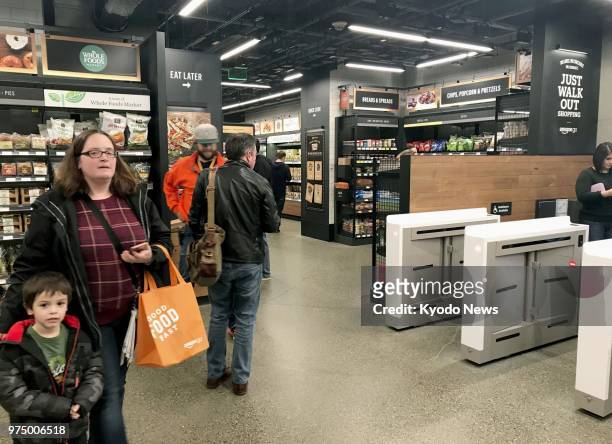 Photo taken in March 2018 shows shoppers at a checkout-free Amazon Go grocery store in Seattle. The store operated by online retailer giant...