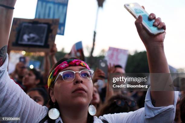 Demonstrator waves an illuminated smartphone towards detainees held at the Metropolitan Detention Center during a Families Belong Together rally in...