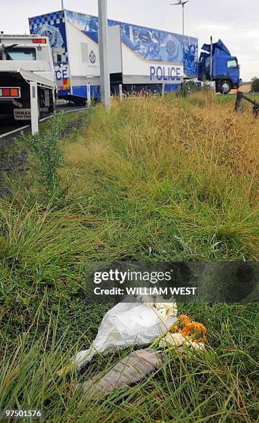 Flowers lay near the site where the body of murdered Indian boy Gurshan Singh was found as a police mobile information centre is parked in the...