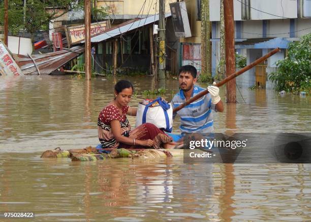 In this picture taken on on June 14 Indian residents sit on a makeshift raft after a heavy downpour at Kailashahar, some 156 kms north of Agartala,...