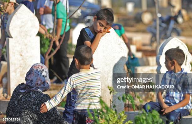 Syrian children visit graves in a cemetery during the celebrations of Eid al-Fitr in Binnish, northwestern Syria, on June 15, 2018. - Muslims...