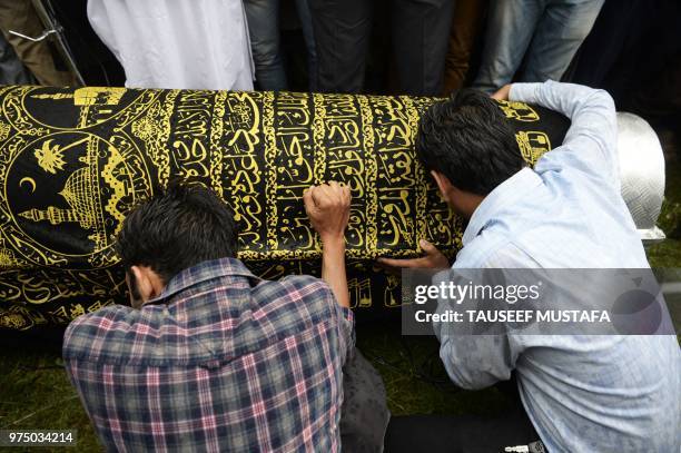 Relatives of slain editor-in-chief of the Srinagar-based newspaper Rising Kashmir Shujaat Bukhari mourn over the coffin during his funeral procession...