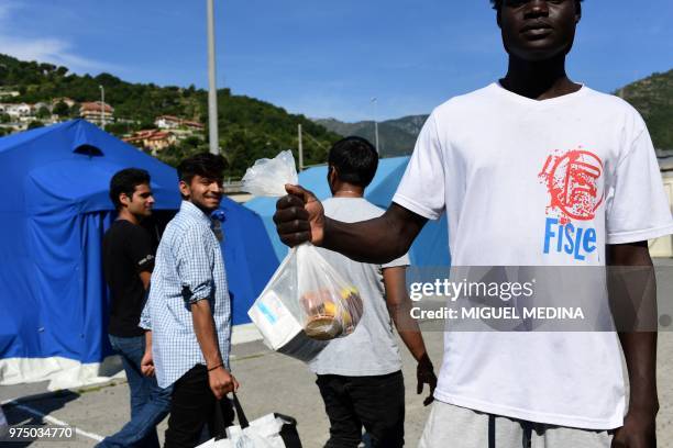 Migrant shows his bag of food as other migrants pass by at the Italian Red Cross camp in Ventimiglia, northern Italy, on June 15, 2018.