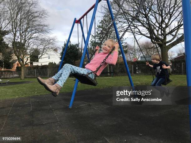 children playing on swings together - sally anscombe stock-fotos und bilder