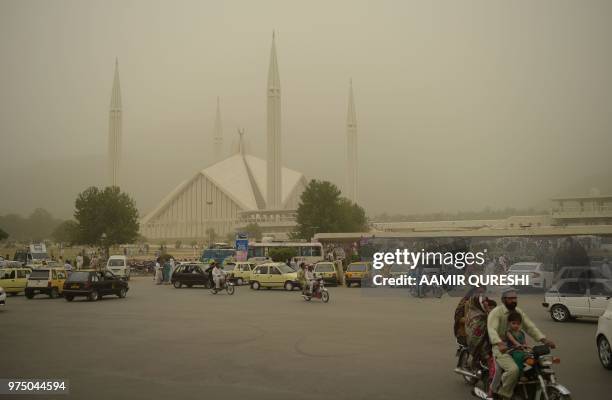 Pakistani Muslims leave the grand Faisal Mosque after Friday prayers as dust covers the sky in Islamabad on June 15, 2018.