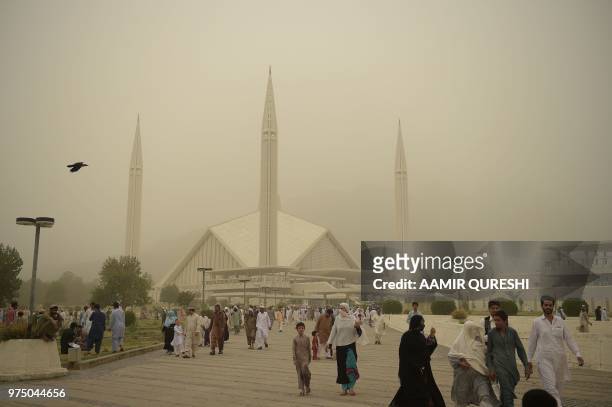 Pakistani Muslims leave the grand Faisal Mosque after the last Friday of the holy month of Ramadan as dust covers the sky in Islamabad on June 15,...