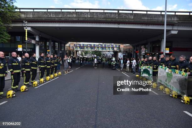 Firefighters line the street join a silent march to St Mark's Park where an open Iftar will take place on the one year anniversary of the Grenfell...