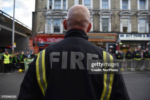 Firefighters line the street join a silent march to St Mark's Park where an open Iftar will take place on the one year anniversary of the Grenfell...