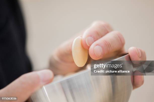 May 2018, Germany, Muenster: A man holding a bowl with altar bread at the service for Ascension Day. From the 09 May until the 13 May Catholic Day is...