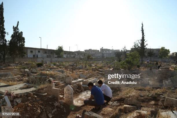 Syrian people visit graves of their relatives following performing Eid al-Fitr prayer in Al-Bab district of Aleppo, Syria on June 15, 2018. Turkey's...