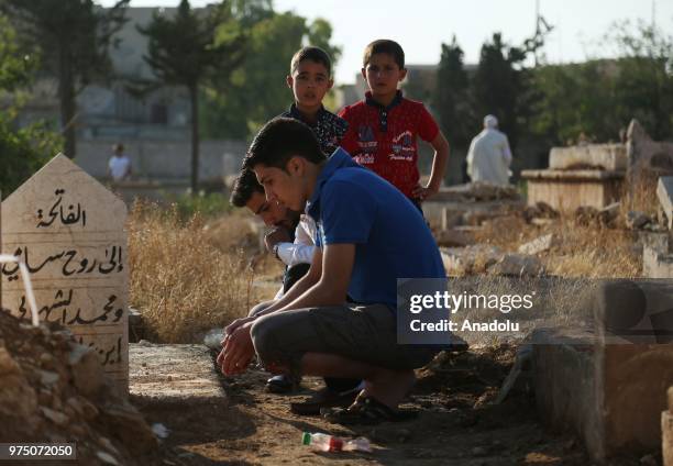 Syrian people visit graves of their relatives following performing Eid al-Fitr prayer in Al-Bab district of Aleppo, Syria on June 15, 2018. Turkey's...