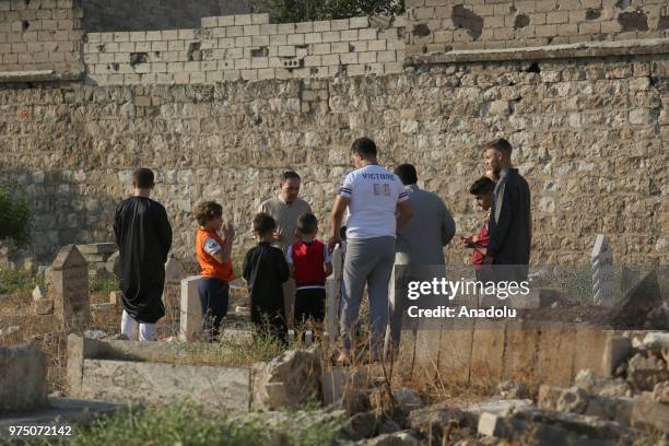 Syrian people visit graves of their relatives following performing Eid al-Fitr prayer in Al-Bab district of Aleppo, Syria on June 15, 2018. Turkey's...