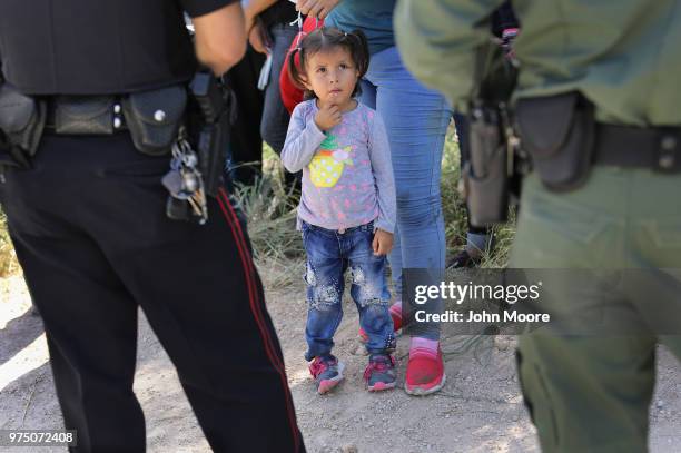 Mission Police Dept. Officer , and a U.S. Border Patrol agent watch over a group of Central American asylum seekers before taking them into custody...