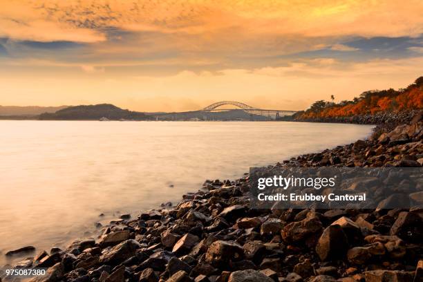 rocky beach with bridge of the americas in background, panama city, panama - bridge of the americas stock pictures, royalty-free photos & images