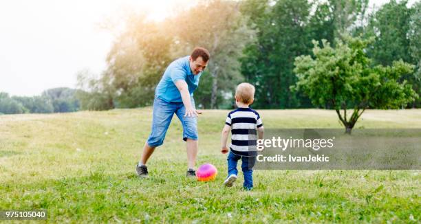 father and son playing soccer in nature - ivanjekic stock pictures, royalty-free photos & images