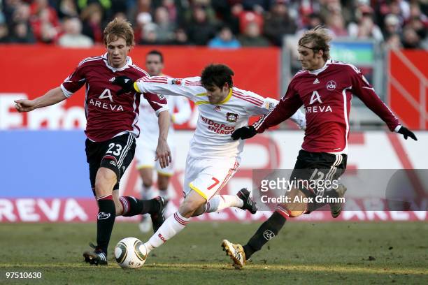 Tranquillo Barnetta of Leverkusen is challenged by Andreas Ottl and Marcel Risse of Nuernberg during the Bundesliga match between 1. FC Nuernberg and...