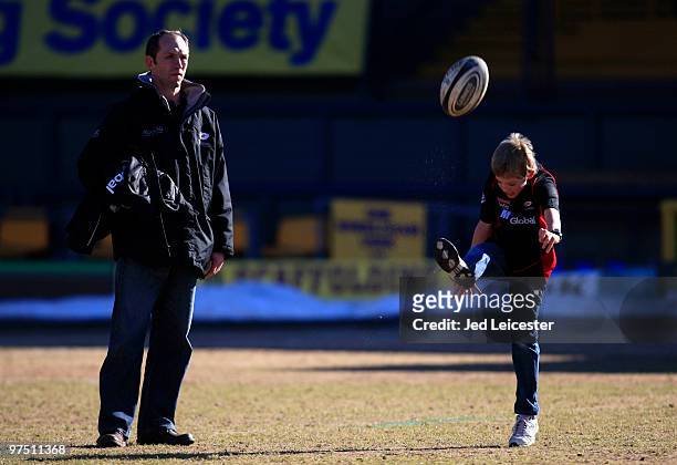 Saracens coach Brendan Venter watches his son play with a rugby ball on the pitch before the match during the Guinness Premiership match between...