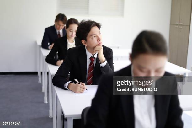 pensive businessman in exam room - tentamenzaal stockfoto's en -beelden